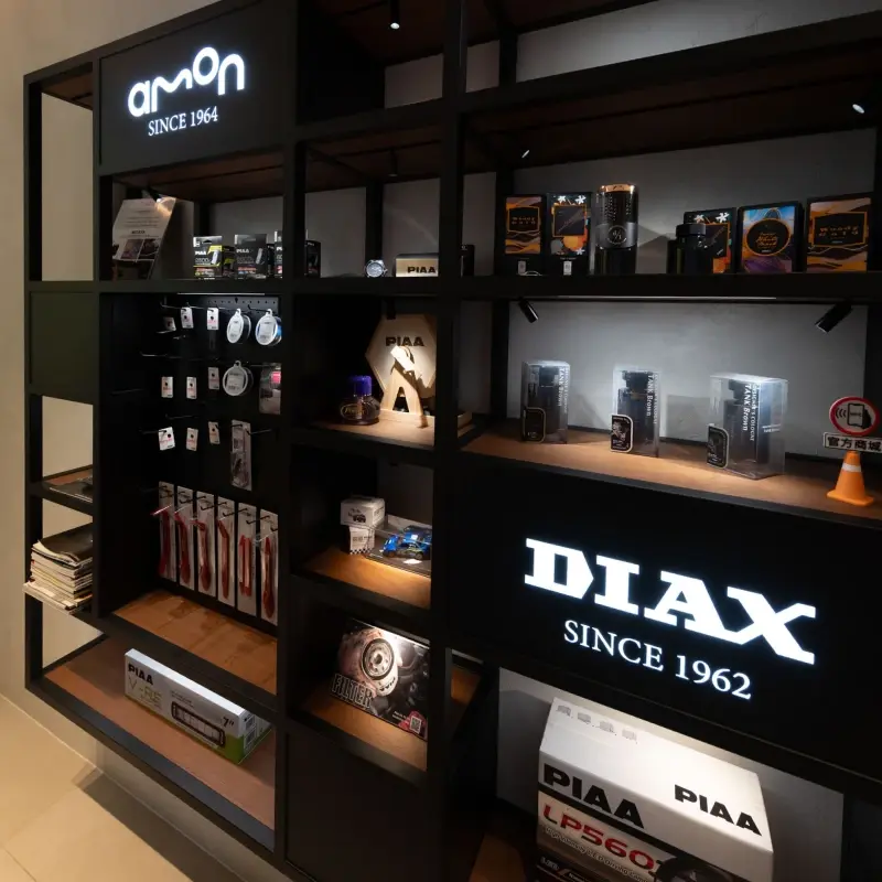 紳新國際總部展示間，AMON 與 DIAX 燈箱招牌下陳列三個品牌的商品